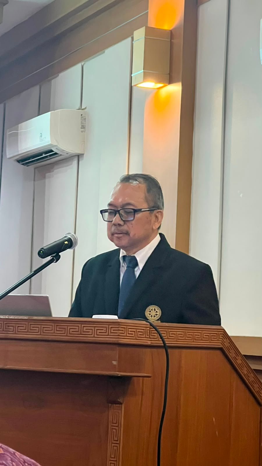 Trisno Nugroho presenting his doctoral research at the podium during the open examination at Udayana University